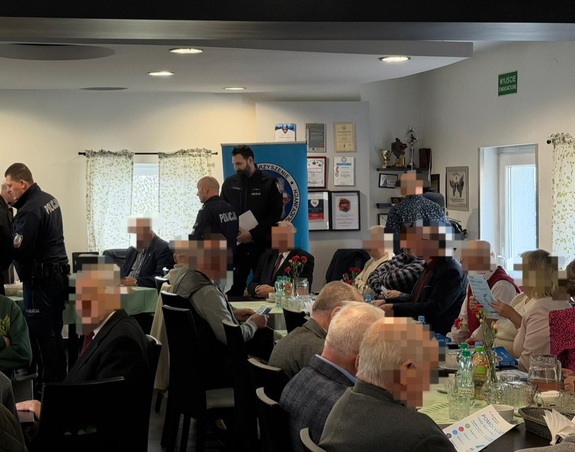 Grupa seniorów siedzących przy stolikach i trzech policjantów