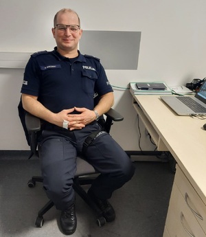 Umundurowany policjant siedzący przy biurku