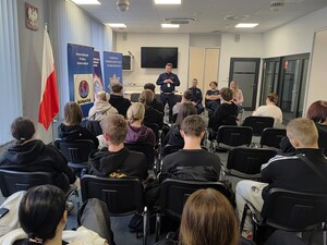 Grupa młodzieży, a przed nimi policjanci i policjantka w stroju cywilnym.