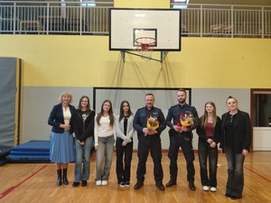 Sześć kobiet w stroju cywilnym oraz dwóch policjantów z kwiatami w ręku