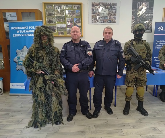 Na zdjęciu dwóch umundurowanych policjantów oraz i dwóch uczniów   w wojskowych strojach,