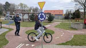 Policjant i jadący na rowerze chłopak po rondzie.