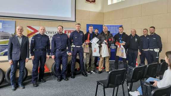 Na zdjęciu pięciu policjantów, trzech mężczyzn e stroju cywilnym oraz trzyosobowa zwycięska drużyna