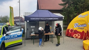 Policyjny namiot, a w nim policjantka. Przed dwóch chłopców.