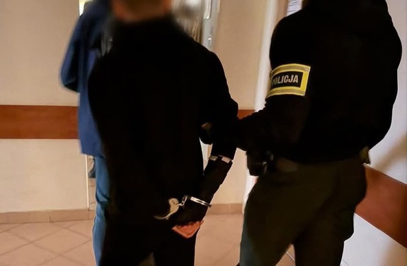 Zatrzymany mężczyzna prowadzony przez nieumundurowanych policjantów