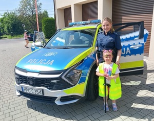 Mała dziewczynka i policjantka na tle radiowozu