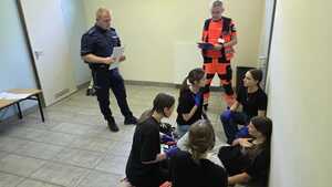Policjant, ratownik medyczny oraz dziewczyny udzielające pomocy poszkodowanej