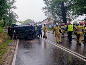 Miejsce kolizji drogowej, samochód przewrócony na bok i służby na drodze