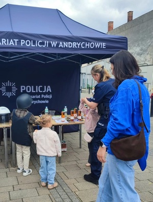Na tle namiotu  policjantka, kobieta i trójka dzieci