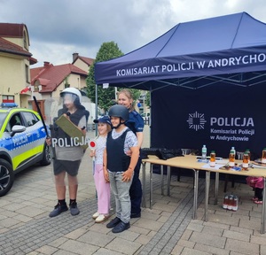 Policjantka oraz trójka dzieci ubranych w elementy umundurowania policyjnego