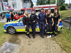 policjanci ze strażakami z OSP pozują do zdjecia na tle oznakowanego radiowozu