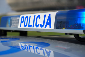 Sygnały świetlne i dźwiękowe na dachu pojazdu. Na białym tle niebieski napis Policja, a po prawej i lewej stronie światła koloru niebieskiego