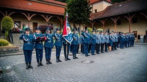 Na placu policjanci i policjantki stojący w szeregach oraz poczet flagowy