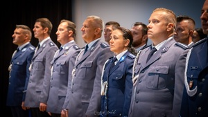 Stojący w szeregu  policjanci i policjantka w umundurowaniu galowym