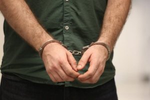 Na rękach mężczyzny założone kajdanki z przodu