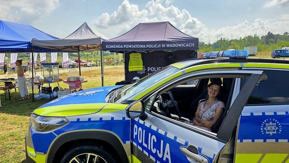 Kobieta siedząca w radiowozie. W tle namioty