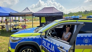 Kobieta siedząca w radiowozie. W tle namioty