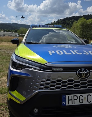 Oznakowany radiowóz, w tle helikopter