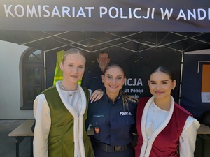 Na tle namiotu policjantka i dwie młode dziewczyny w strojach ludowych
