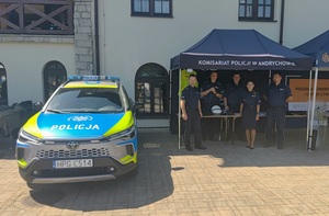 Pod namiotem czterech policjantów i policjantka, po lewej radiowóz