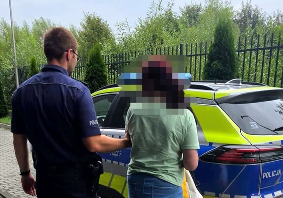 Policjant i zatrzymana kobieta na tle radiowozu