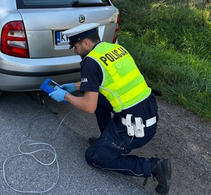Kontrola emisji spalin w pojeździe sprawdzana przez policjanta ruchu drogowego