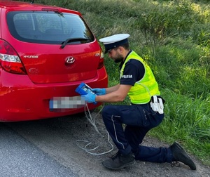 Policjant ruchu drogowego kontrolujący w pojeździe emisję spalin