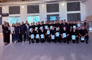 Zdjęcie grupowe, na którym są uczniowie klas policyjnych, policjant i policjantki oraz kobiety i mężczyźni w stroju cywilnym