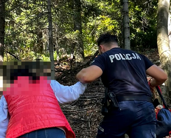 Policjant prowadzący kobietę w lesie