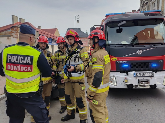 Na zdjęciu czterech strażaków, policjant i wóz strażacki