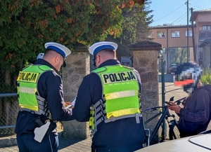 Dwaj policjanci ruchu drogowego i chłopiec w kasku na rowerze