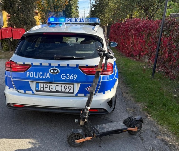 Na tle oznakowanego radiowozu hulajnoga elektryczna