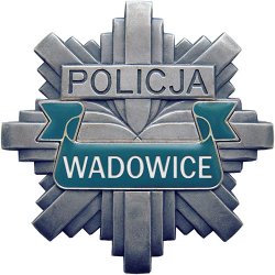 Odznaka policyjna koloru szarego, na której widnieje napis Policja Wadowice