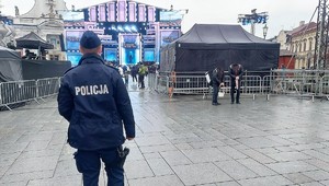 Umundurowany policjant stojący tyłem. W tle scena i ludzie.