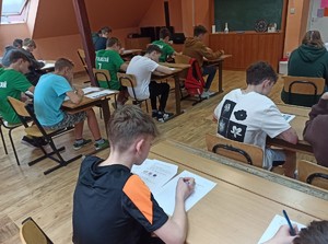 Uczniowie siedzący w klasie, którzy rozwiązują test