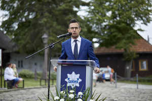 Poseł na Sejm RP przemawia, stoi za mównicą na której jest logo Policji.